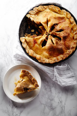 Pie crust design ideas - various ways of pie decoration with lattice and leaves. Apple, strawberry and raspberry pies cooked and served with tea on white marble table, apple pie sliced