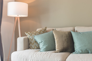 set of pillows on cozy gray sofa with wooden lamp