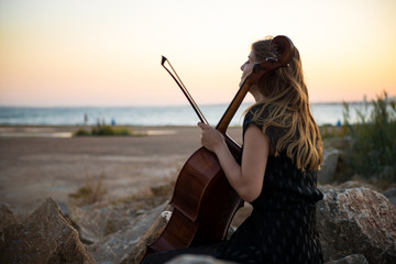 Young beautiful girl with her cello on the outside