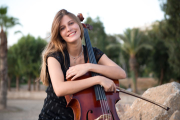 Happy young beautiful girl with her cello on the outside © luismolinero