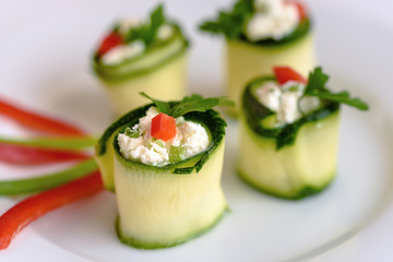 Rolls of zucchini stuffed with cheese and chives and red paprika.