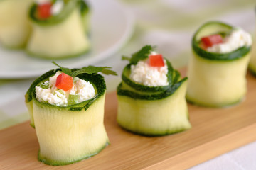 Rolls of zucchini stuffed with cheese and chives and red paprika.