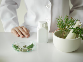 scientist or doctor making herbal medicine with herb leaves , capsule, tablets. hands.