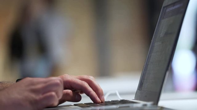 Man types text on laptop.