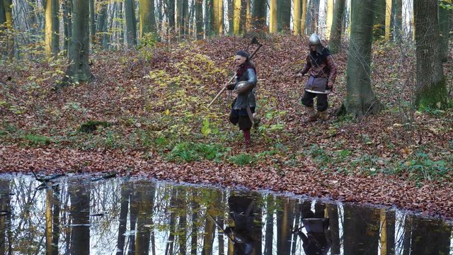 Medieval Vikings walking through the forest. Reenactment.
