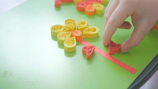 Child glues curly paper in leaf shape