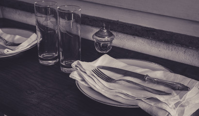 Abandoned table with old dishes, glasses and cutlery