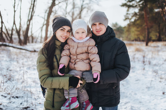 Portrait of Young family and his baby in a winter park. Beautiful daugther.
