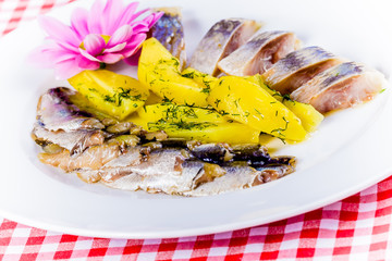 Salted herring and mackerel with boiled potatoes on white plate