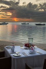 Festlich gedeckter Tisch am Strand bei Sonnenuntergang in Le Morne, Mauritius, Afrika.