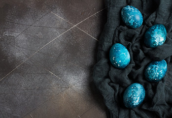 Easter eggs painted by hand in blue color on dark background