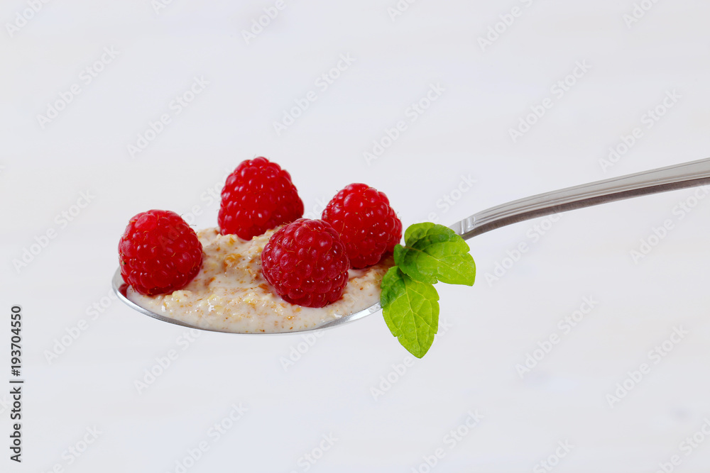 Sticker spoon of oatmeal porridge with raspberries