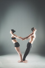 Young couple practicing acro yoga on mat in studio together. Acroyoga. Couple yoga. Partner yoga.