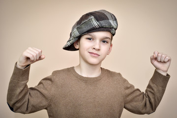 Cute young boy with cap showing his strong arms. Vintage style.