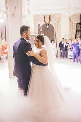 Wedding of beautiful caucasian couple just married and dancing their first dance. Bride and groom in wedding restaurant hall