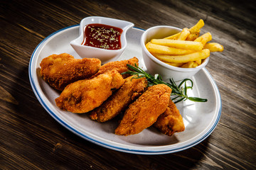 Chicken nuggets with french fries on wooden table 