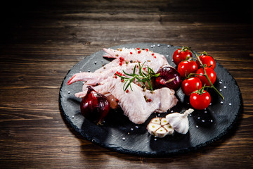 Raw chicken wings on black stone on wooden background 