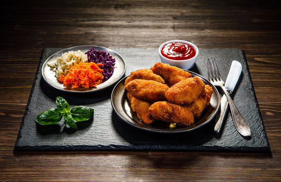     Chicken nuggets with vegetable salad on wooden table 