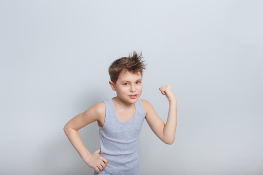 Smiling Boy In A Grey Tank Top Shows Biceps On A Blue Background