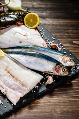 Raw fishes on black stone on wooden table