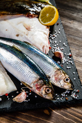Raw fishes on black stone on wooden table