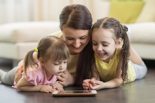 Happy woman and her children using digital tablet on floor at home