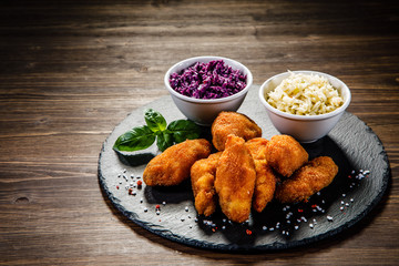 Fried chicken nuggets with cabbage served on black stone on wooden table