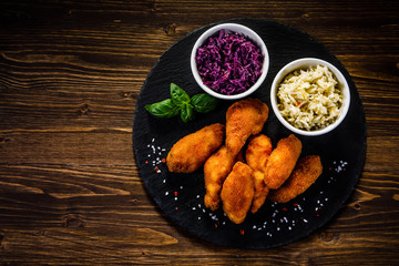 Fried chicken nuggets with cabbage served on black stone on wooden table