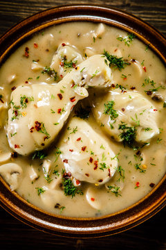 Chicken legs with champignon sauce on wooden table