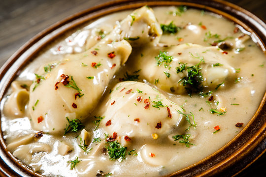 Chicken legs with champignon sauce on wooden table