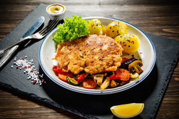 Fried pork chop with potatoes served on black stone