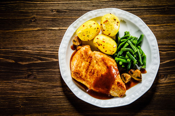 Grilled chicken fillet and vegetables on wooden table