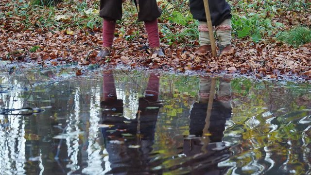 Legs of medieval Vikings in the forest reflected in water near lake