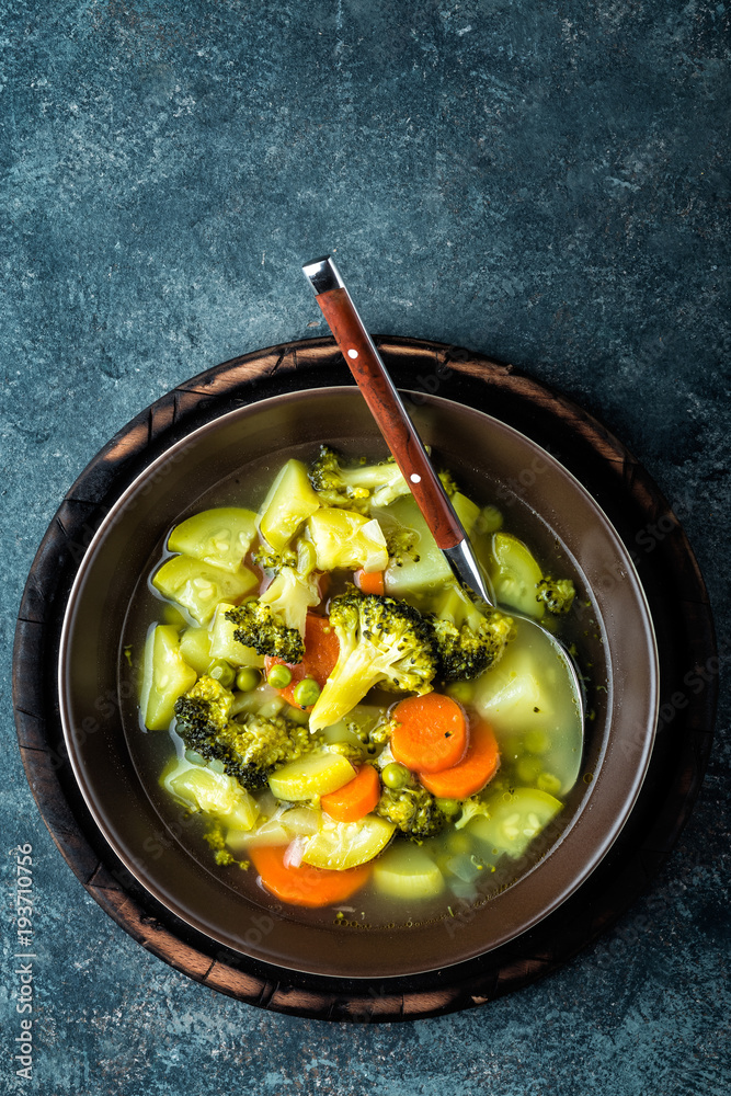 Wall mural plate of fresh hot vegetable soup with broccoli, potato, green peas, onion and carrot. healthy vegan