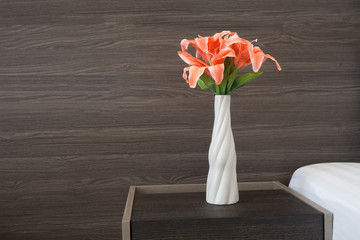 Beautiful pink flower on pot with wood texture background in bedroom.