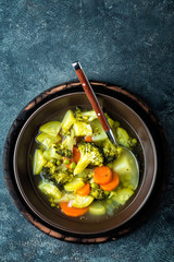 plate of fresh hot vegetable soup with broccoli, potato, green peas, onion and carrot. healthy vegan diet food, top view