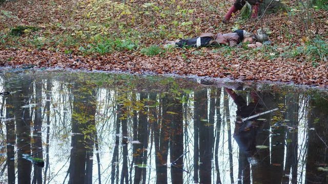Two warriors Viking are fighting with swords in the forest reflected in water.