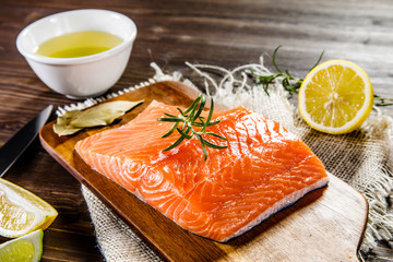 Fresh raw salmon fillet on cutting board on wooden background