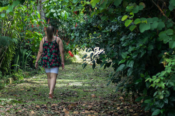 Woman walking along the green forest trail