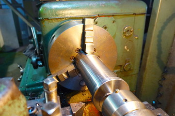 Processing of the shaft with a chisel on a lathe, with shavings at a manufacturing plant in disassembled form close-up.