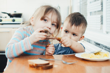 Children in the kitchen eat meat and mashed potatoes, very fun, share and feed each other