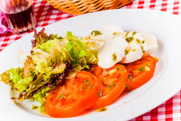 Caprese salad with herbs and spices on white plate