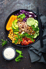 Buddha bowl dish with brown rice, avocado, pepper, tomato, cucumber, red cabbage, chickpea, fresh lettuce salad and walnuts. Healthy vegetarian eating, super food. Top view