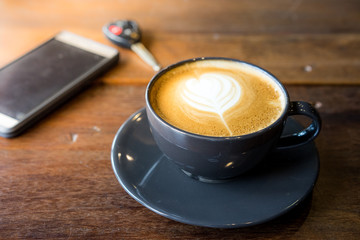 Coffee cup with latte art on the wooden table.