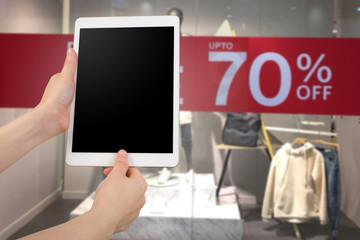 human hand hold blank screen smart phone, tablet, cellphone on  Discount label at cloth store background.