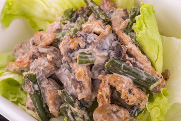 Salad with pieces of chicken, mushrooms and siliculose haricot with lettuce leaves