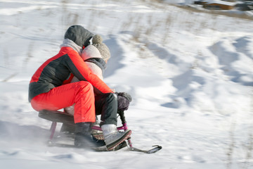 Fototapeta na wymiar Дети на снегокате катятся с горы