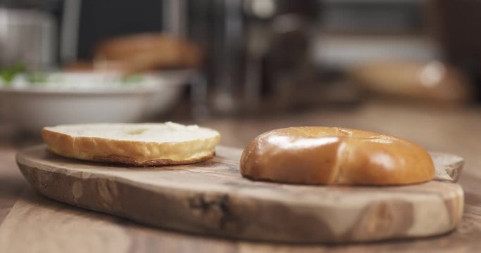 Man hands making bagel sandwich with prosciutto and cream cheese on wood board