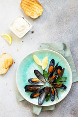 Mussels boiled in a sauce of white wine, served with toast, garlic sauce and lemon. Gourmet italian cuisine. Flat lay. Top view.