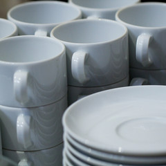 pile of white clean cups and saucers in a public cafe, prepared for tea or coffee